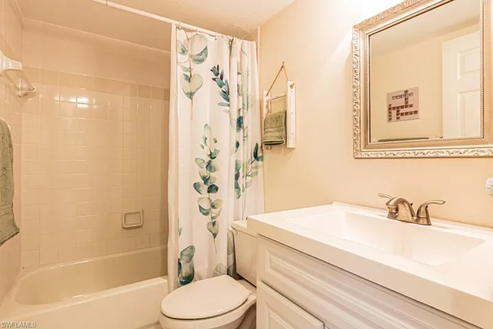 Full bathroom with toilet, shower / bath combination with curtain, and vanity