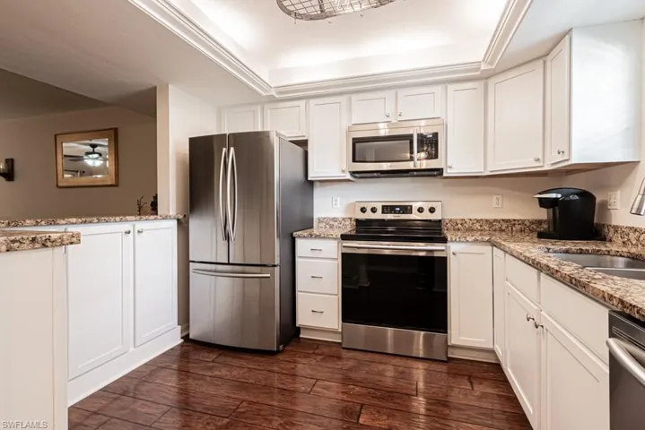 Kitchen featuring white cabinets, appliances with stainless steel finishes, and dark wood-type flooring