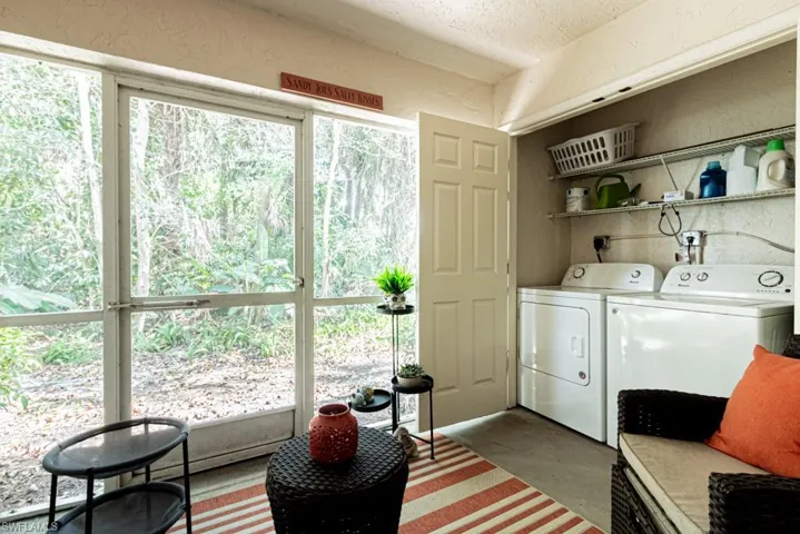 Laundry room featuring a textured wall, washer and clothes dryer, laundry area, and a textured ceiling