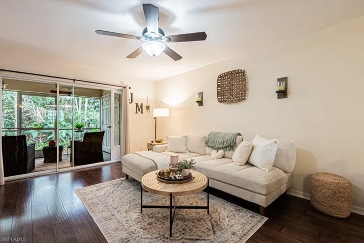 Living room with dark wood finished floors, baseboards, and ceiling fan