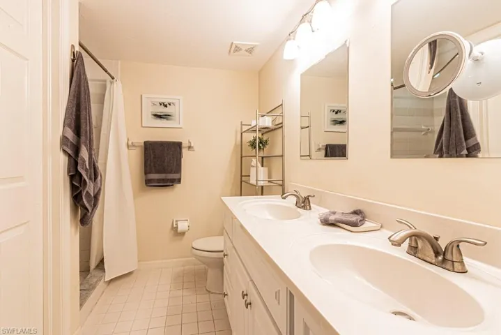 Bathroom featuring tile patterned floors, visible vents, toilet, and a sink
