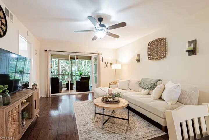 Living room featuring a ceiling fan, dark wood-type flooring, and visible vents