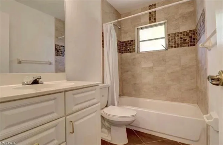Full bathroom with shower / bath combination with curtain, tile patterned flooring, toilet, and vanity