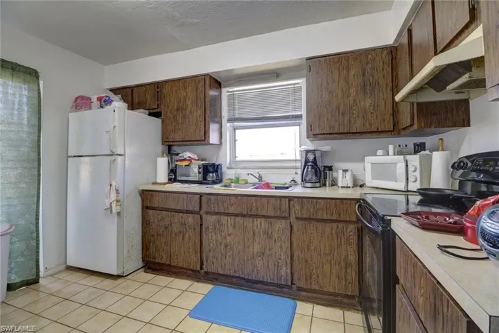 Kitchen featuring sink, light tile patterned floors, and white appliances