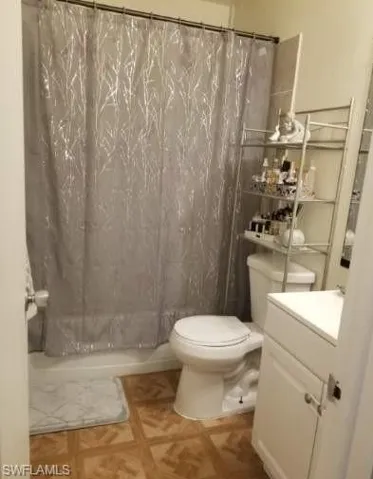 Bathroom featuring vanity, toilet, a shower with curtain, and parquet flooring
