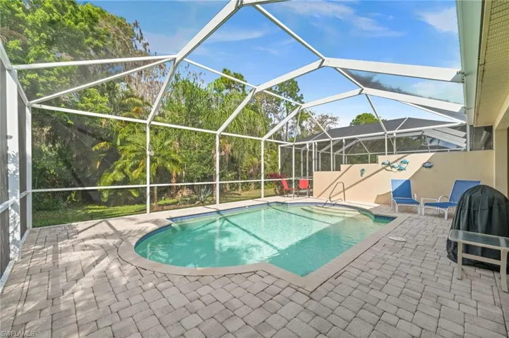 Outdoor pool with a patio, a sunroom, glass enclosure, and a jacuzzi