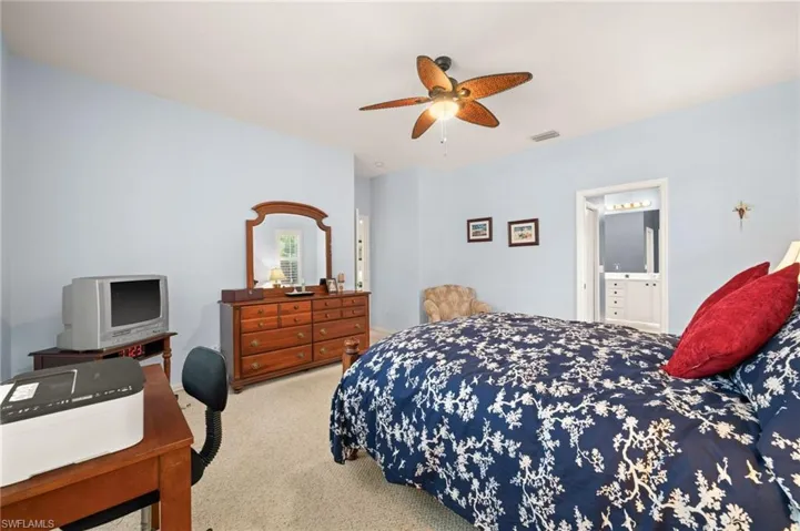Carpeted bedroom featuring ceiling fan and ensuite bath
