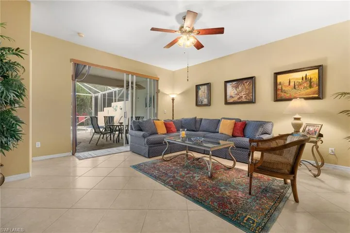 Living room with a sunroom, a ceiling fan, and light tile patterned flooring