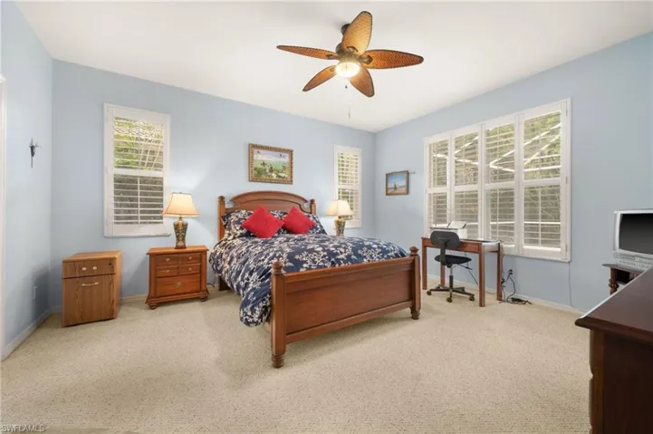 Carpeted bedroom with a ceiling fan and a desk