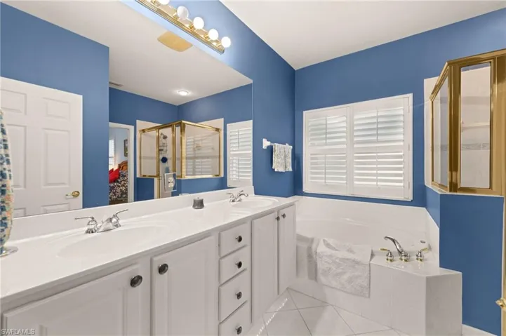 Full bathroom featuring a stall shower, a garden tub, double vanity, and light tile patterned flooring
