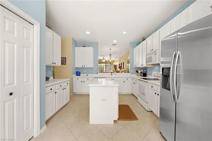 Kitchen featuring white appliances, hanging lights, light countertops, and a kitchen island