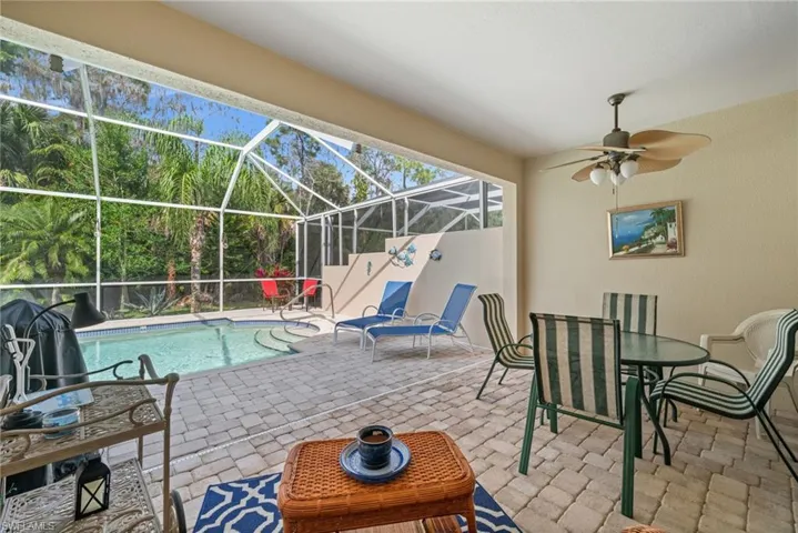 View of patio with a sunroom, glass enclosure, an outdoor pool, outdoor dining area, and ceiling fan