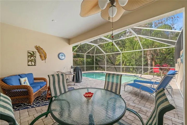 Outdoor pool featuring a sunroom, a patio area, and glass enclosure