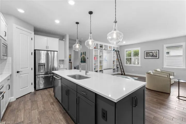 Kitchen featuring sink, white cabinetry, an island with sink, stainless steel appliances, and decorative backsplash