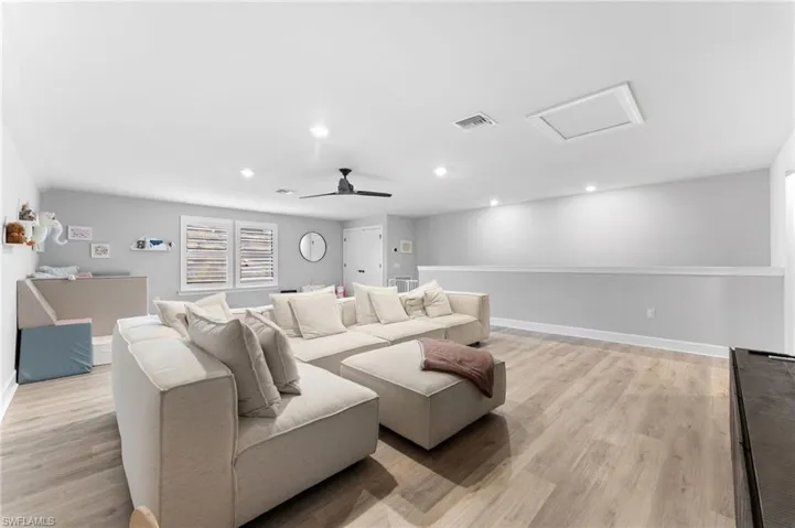 Home theater room with ceiling fan and light hardwood / wood-style flooring