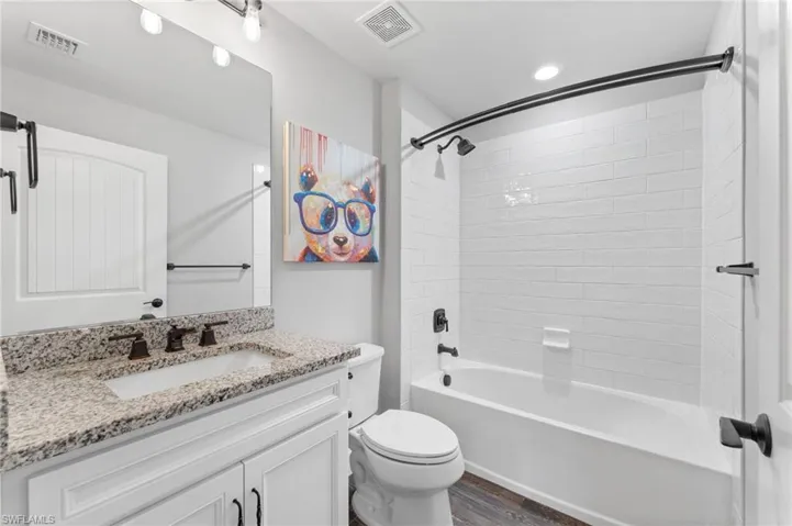 Full bathroom with hardwood / wood-style flooring, vanity, toilet, and tub / shower combination