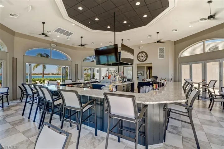 Kitchen featuring crown molding, a raised ceiling, light stone countertops, and a high ceiling