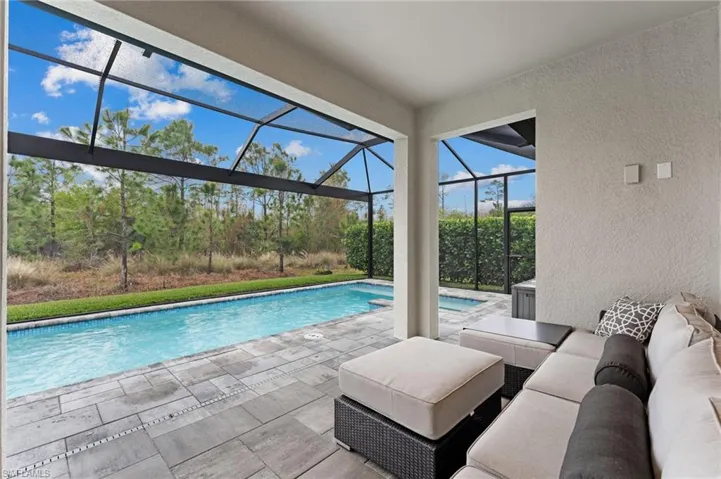 View of swimming pool with an outdoor hangout area, a patio, and glass enclosure