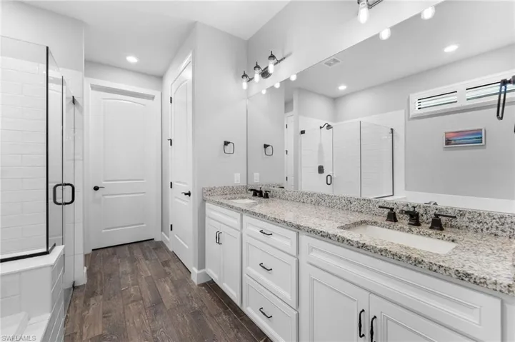 Bathroom featuring a shower with door, wood-type flooring, and vanity
