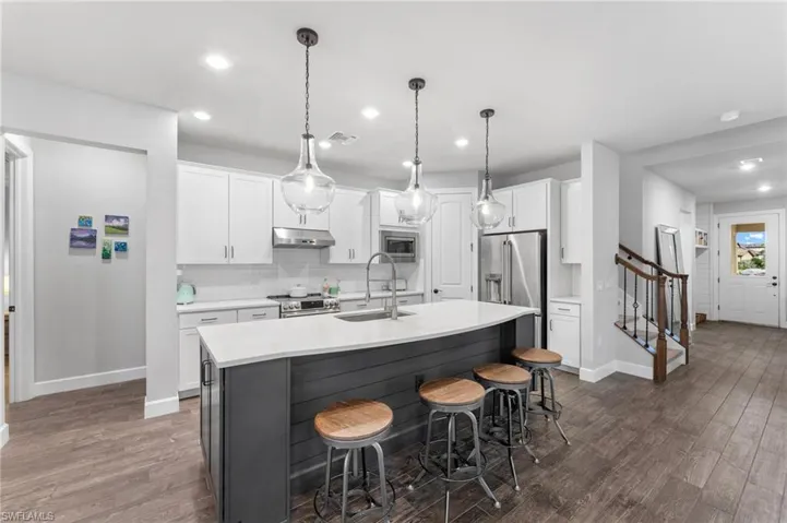 Kitchen with white cabinetry, sink, a center island with sink, and appliances with stainless steel finishes