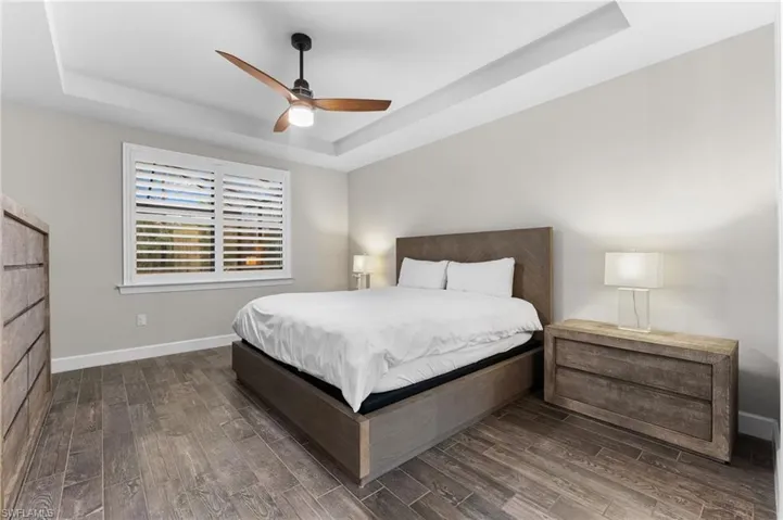 Bedroom featuring ceiling fan, dark hardwood / wood-style floors, and a raised ceiling