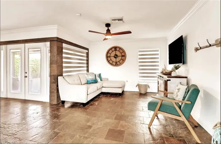 Living room featuring crown molding, ceiling fan, and french doors