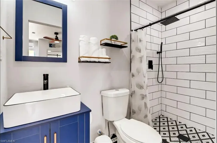 Bathroom with tiled shower, toilet, and vanity