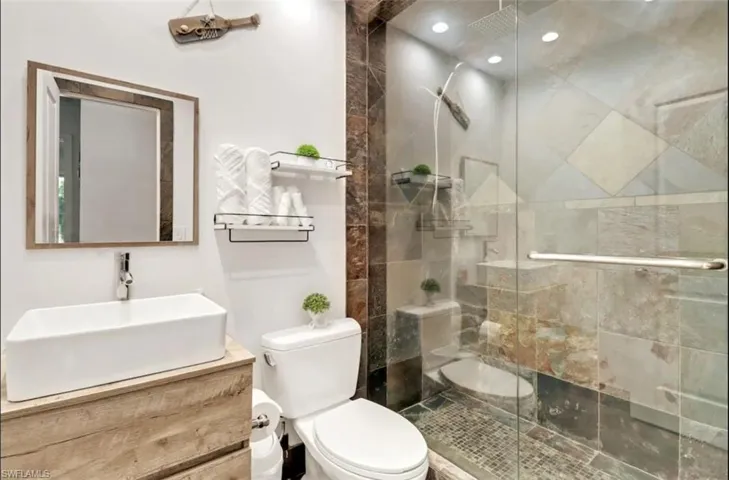 Bathroom featuring vanity, toilet, and a shower with shower door