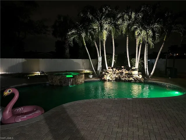 Pool at night featuring a patio area