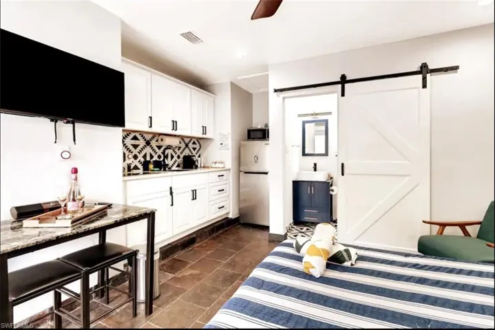Kitchen with a barn door, white cabinets, ceiling fan, and stainless steel appliances