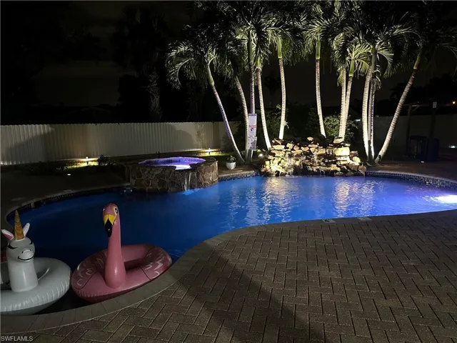 Pool at twilight with a patio area and an in ground hot tub