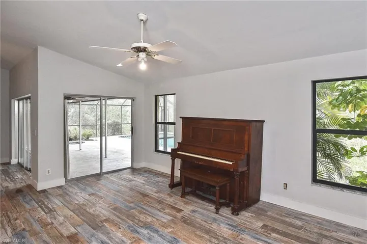 Living area with ceiling fan, dark hardwood / wood-style flooring, and vaulted ceiling