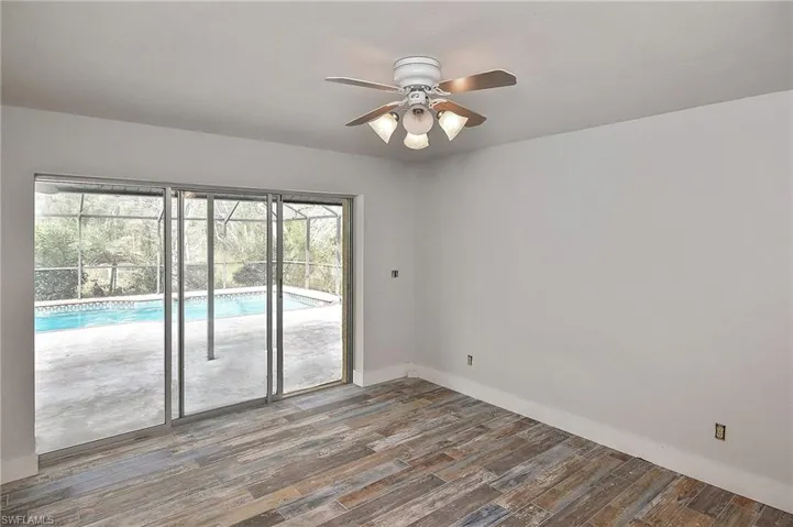 Empty room with ceiling fan and dark hardwood / wood-style floors