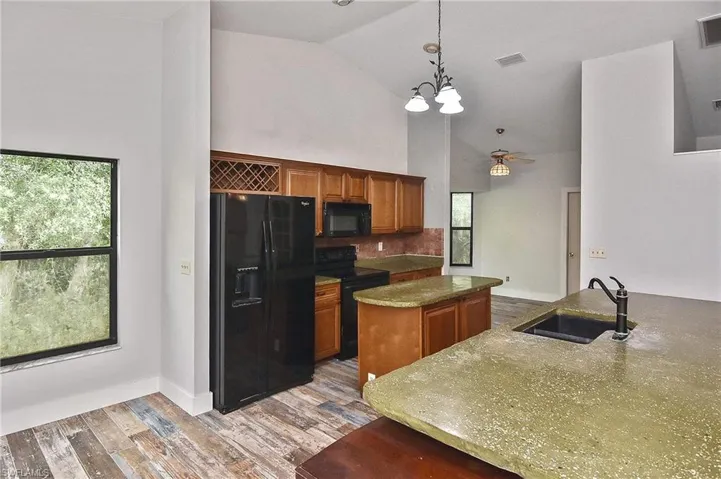 Kitchen featuring a kitchen island, sink, hanging light fixtures, light hardwood / wood-style floors, and black appliances