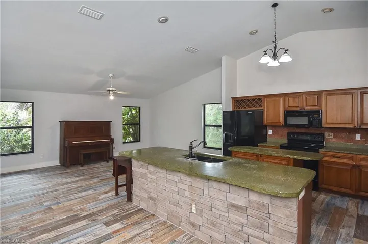 Kitchen featuring sink, wood-type flooring, hanging light fixtures, plenty of natural light, and black appliances