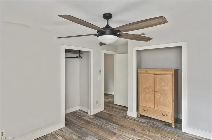 Unfurnished bedroom with ceiling fan and dark hardwood / wood-style flooring