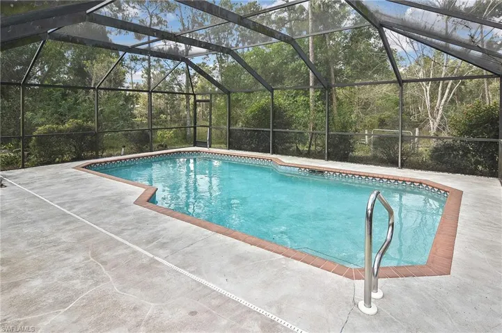 View of pool with a patio and glass enclosure