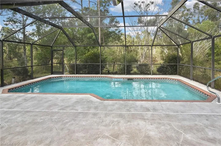 View of pool with a patio and glass enclosure