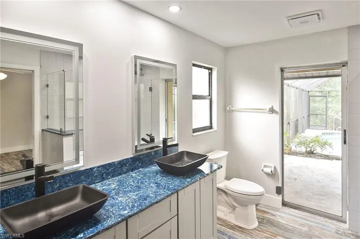 Bathroom with walk in shower, hardwood / wood-style floors, vanity, and toilet