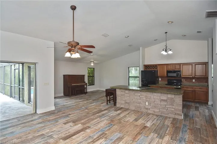 Kitchen with sink, wood-type flooring, high vaulted ceiling, hanging light fixtures, and black appliances