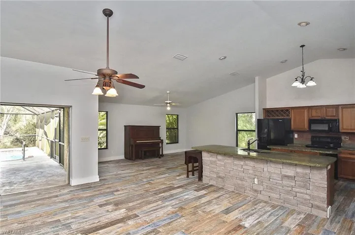 Kitchen with hardwood / wood-style flooring, pendant lighting, sink, and black appliances