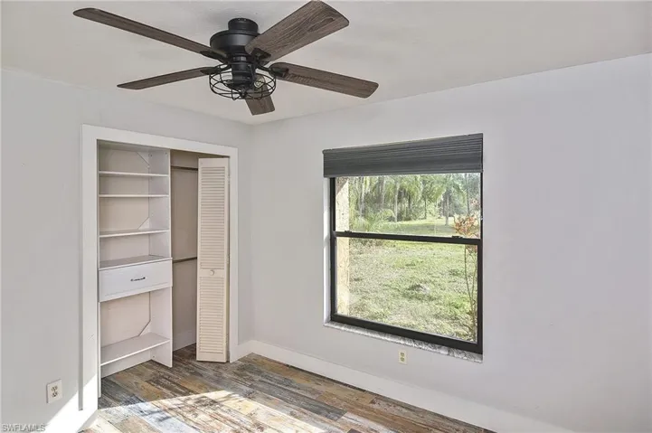 Unfurnished bedroom with dark hardwood / wood-style flooring, a closet, and ceiling fan