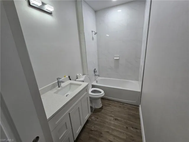 Full bath featuring wood finished floors, vanity, and shower / tub combination