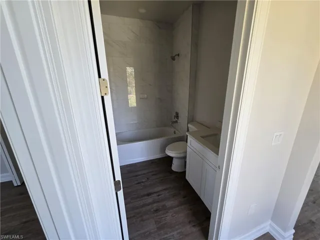 Bathroom with vanity, wood finished floors, and shower / washtub combination