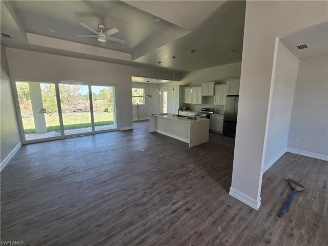 Kitchen with open floor plan, freestanding refrigerator, electric stove, white cabinetry, and dark wood finished floors