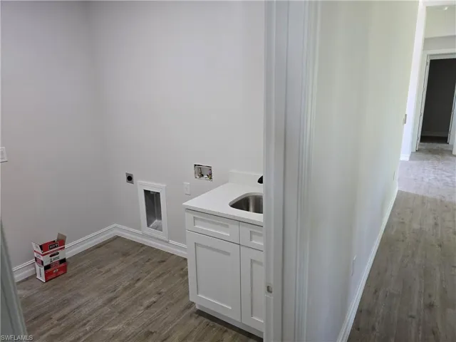 Washroom featuring dark wood-style floors, hookup for a washing machine, hookup for an electric dryer, and cabinet space