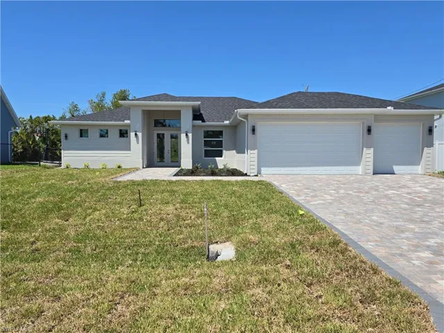 Prairie-style home with french doors, an attached garage, a front yard, decorative driveway, and stucco siding