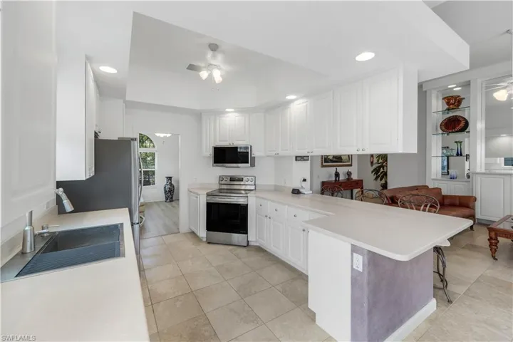 Kitchen with a kitchen breakfast bar, ceiling fan, a peninsula, appliances with stainless steel finishes, and light countertops