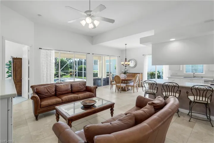 Living room with plenty of natural light, a ceiling fan, a chandelier, light tile patterned floors, and recessed lighting