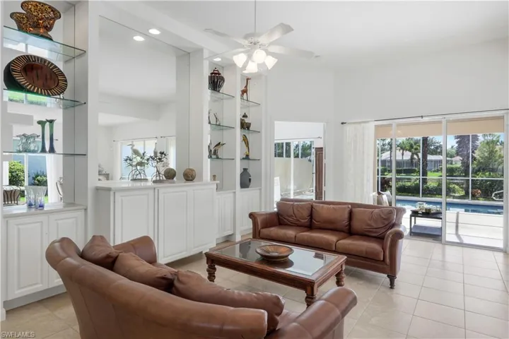 Living room featuring built in shelves, recessed lighting, light tile patterned floors, a ceiling fan, and a high ceiling